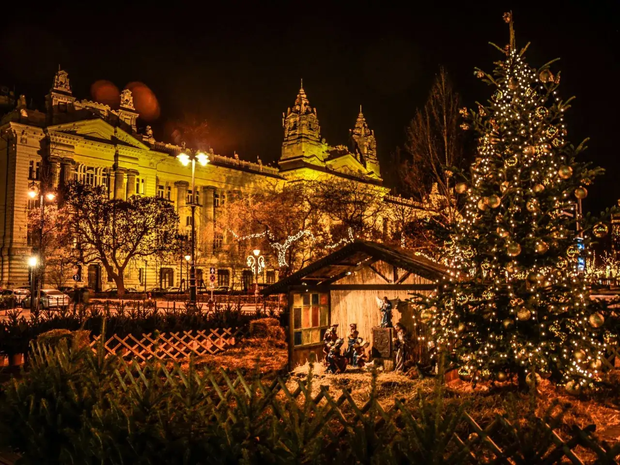 Budapeszt jarmark bożonarodzeniowy: choinka, szopka i iluminacje na tle zabytkowej budowli.