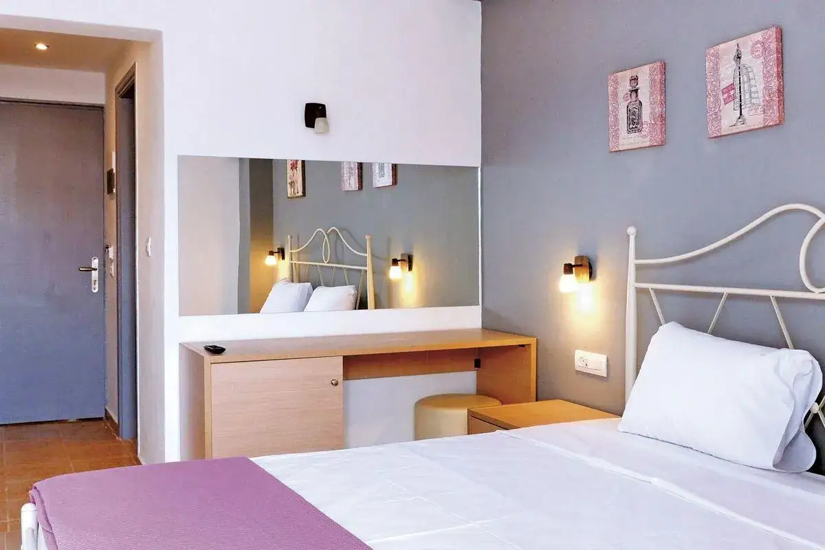 Pok&oacute;j w hotelu Island Maya Resort: ł&oacute;żko z białym pościelą i fioletowym pledem, lustro, toaletka, drzwi.