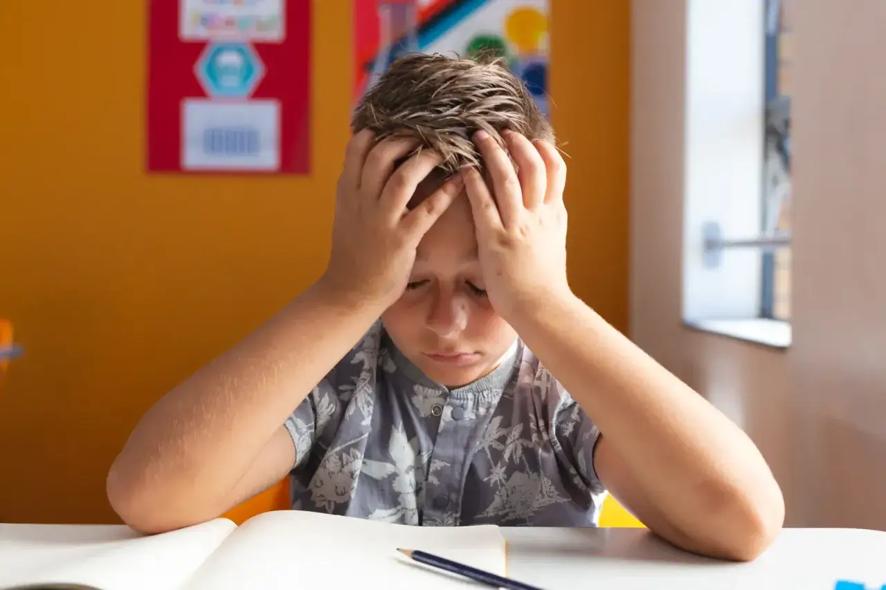 Dziecko z ADHD pr&oacute;buje się skupić, chaos w tle