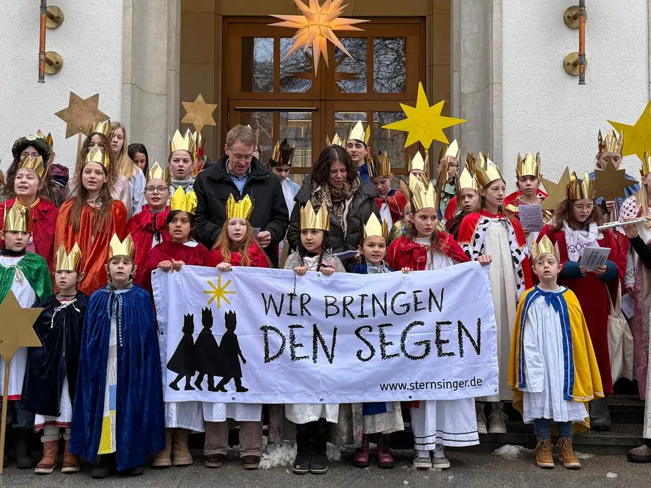 Sternsinger am 6. Januar bringen den Segen. Kinder mit Kronen und Gew&auml;ndern halten ein Banner mit der Aufschrift 
