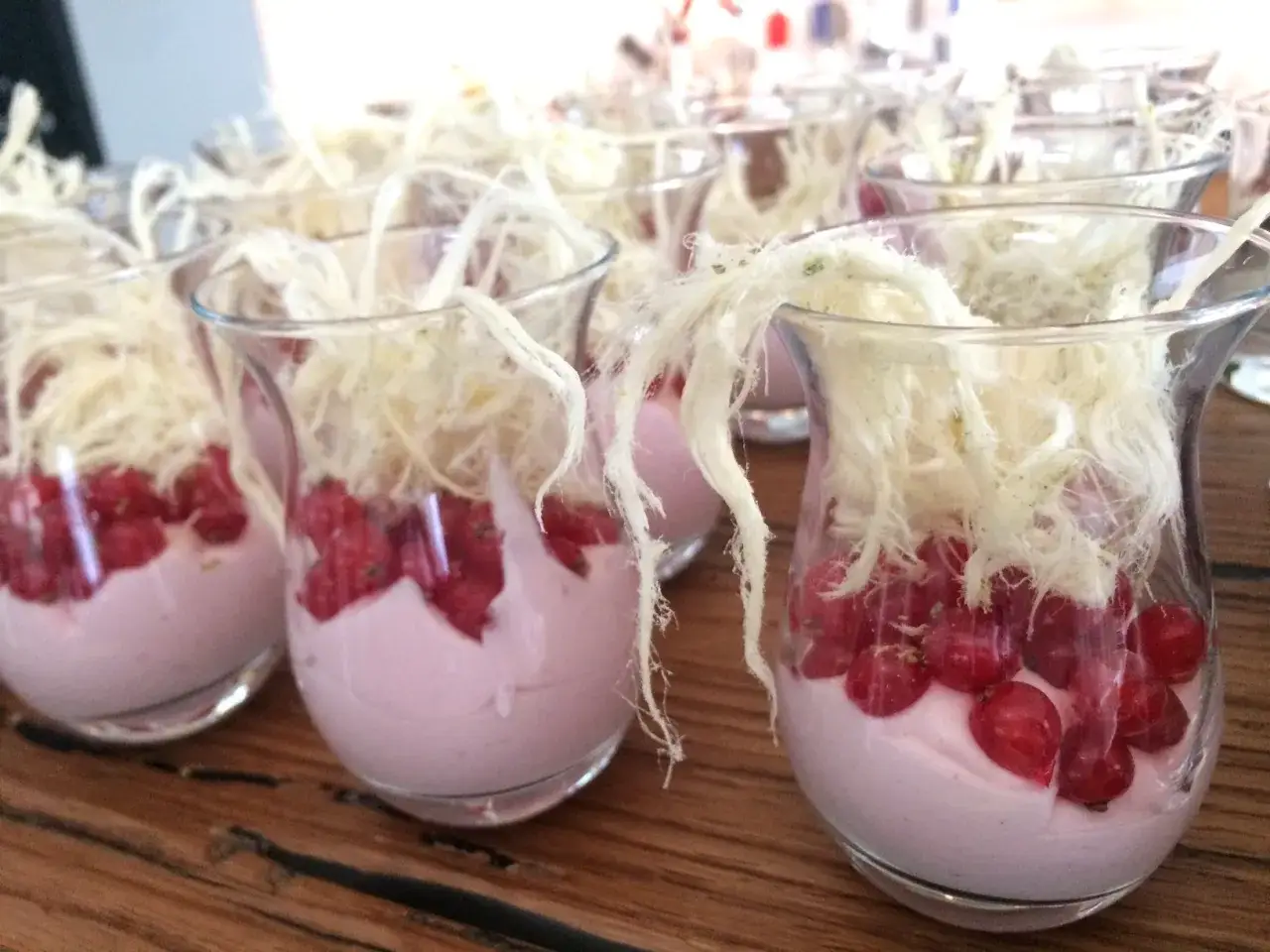 Kleine Gläser mit rosa Creme, roten Johannisbeeren und Zuckerwatte. Perfekt für Johannisbeeren Rezepte.