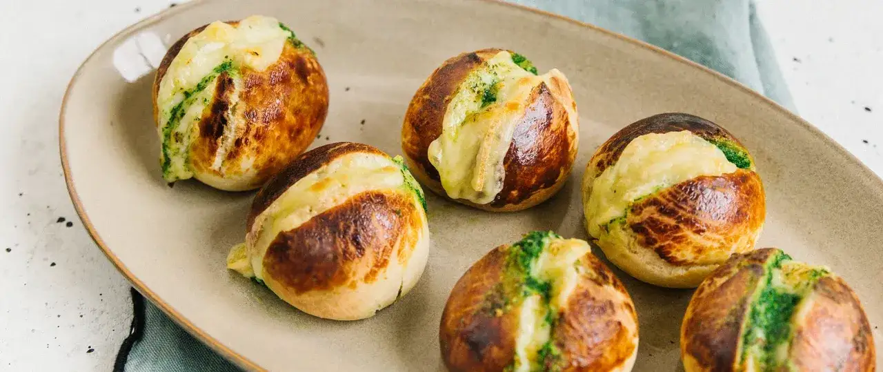 Petits pains dor&eacute;s garnis de fromage fondant et d'herbes, &eacute;voquant le go&ucirc;t du beurre normandie.