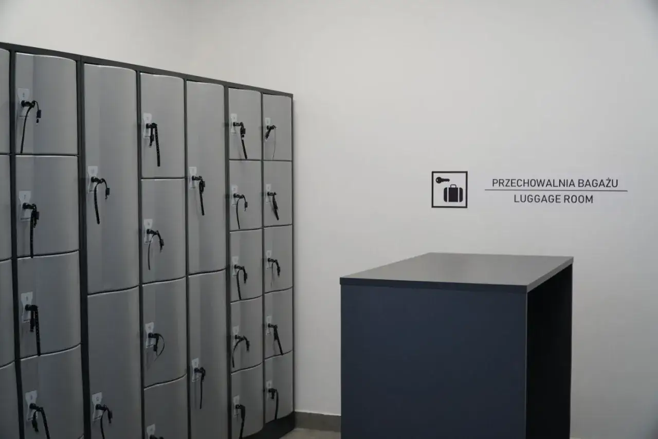 Rzędy szarych szafek z kluczami czekają na bagaż. Obok znak