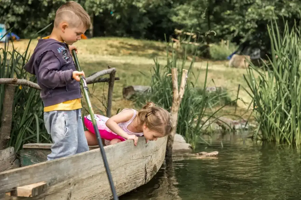 Dzieci łowią ryby z łódki na Kaszubach. Wspaniałe atrakcje Kaszuby dla dzieci, które odkrywają uroki natury.