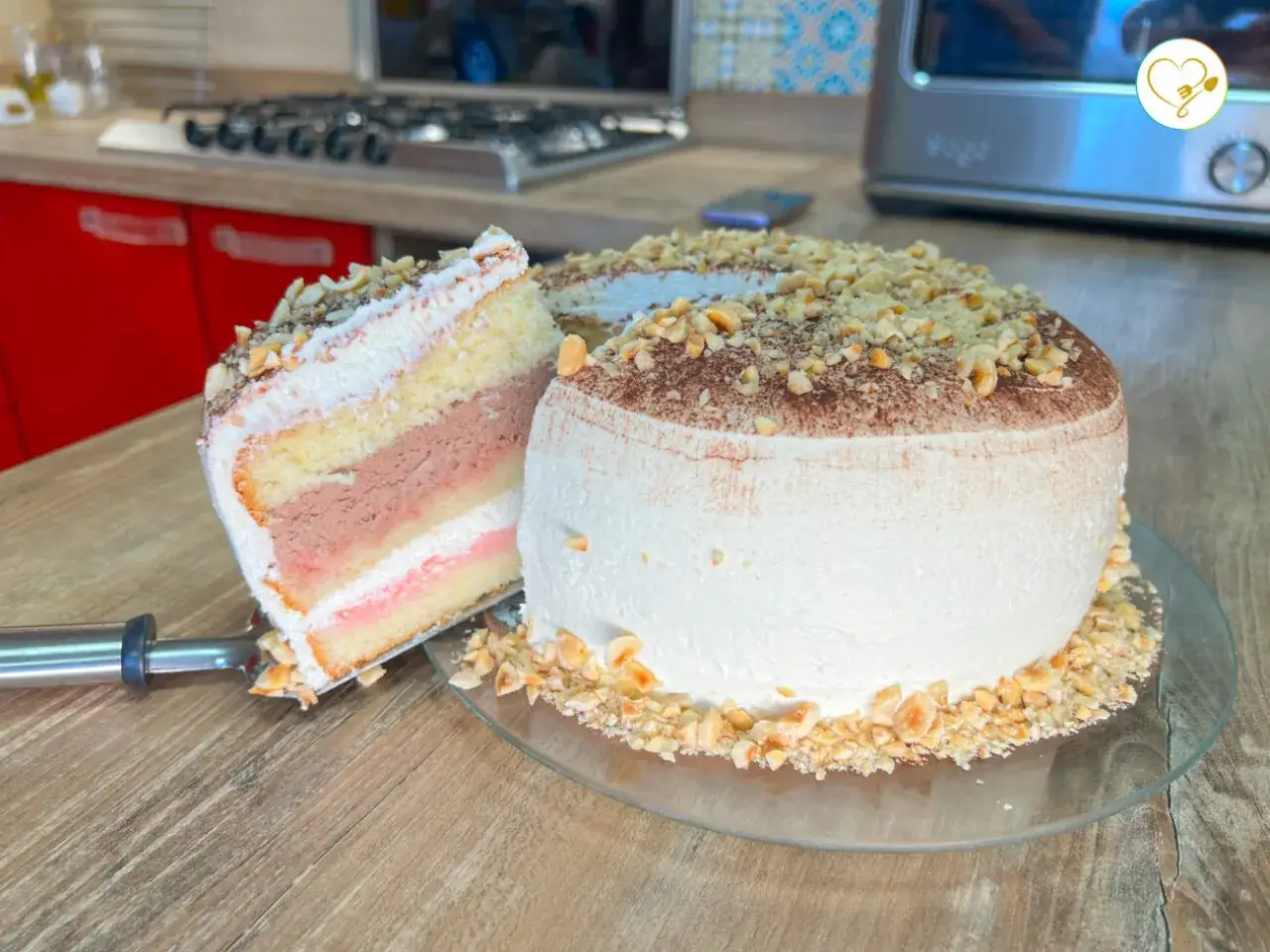 Torta soffice con crema al mascarpone e cacao, guarnita con nocciole tritate. Una fetta mostra gli strati golosi, perfetta per il pan di spagna.