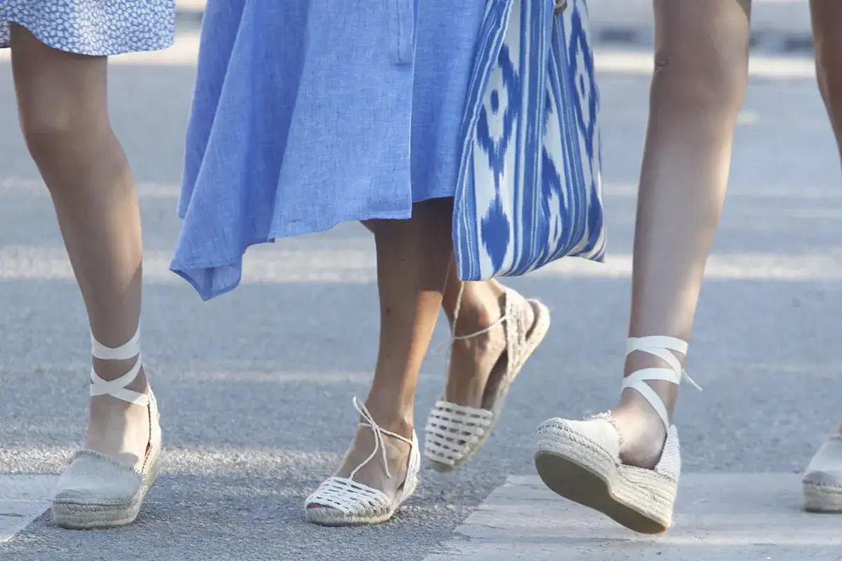 Pies con alpargatas reina Letizia, unas de cuña con lazada y otras planas de esparto, paseando con un bolso estampado.