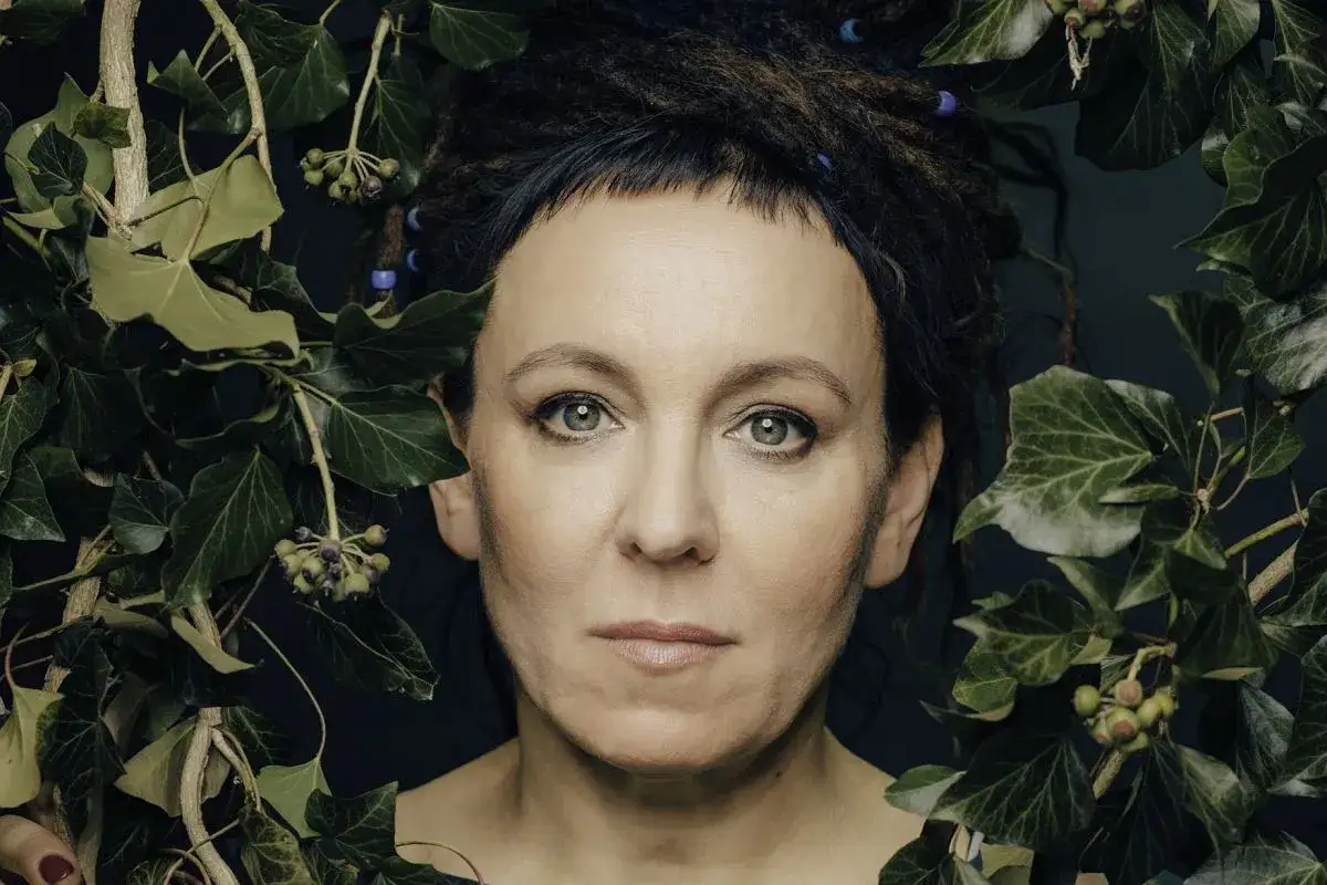 Olga Tokarczuk, jej wiek nie ma znaczenia, gdy otaczają ją liście bluszczu.