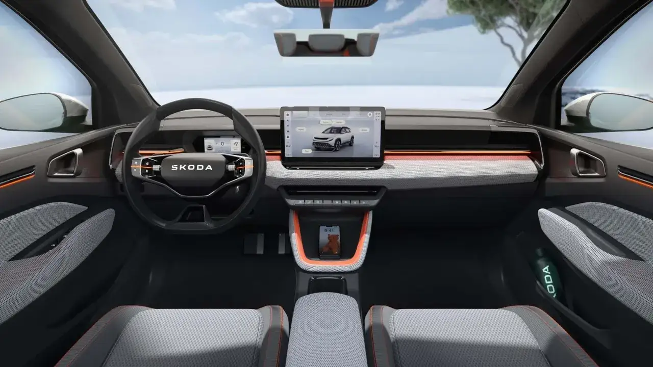 Interno moderno della Skoda Epiq con ampio display centrale, volante tecnologico e dettagli arancioni.