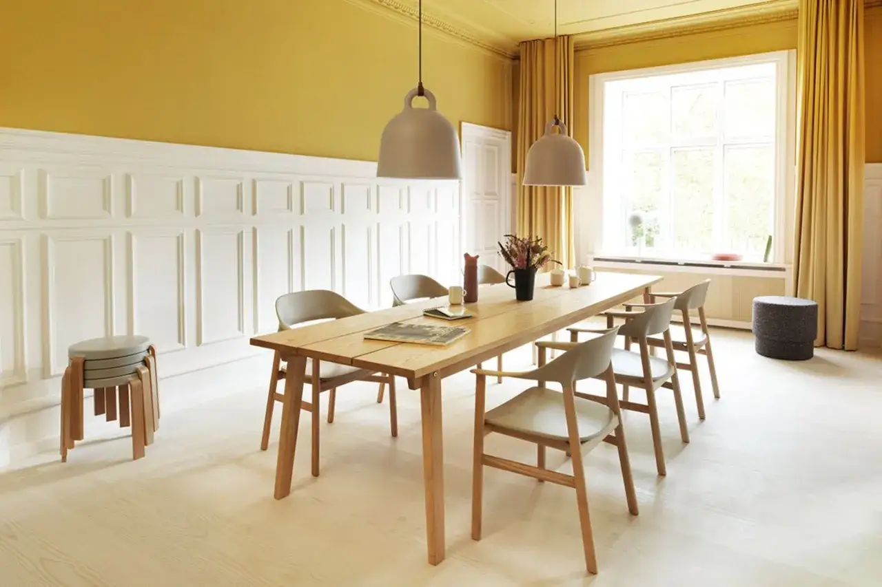 Helle Esszimmer Wand Ideen mit Paneelen und einem Holztisch. Ein sonnengelber Raum mit Vorhängen und modernen Stühlen.
