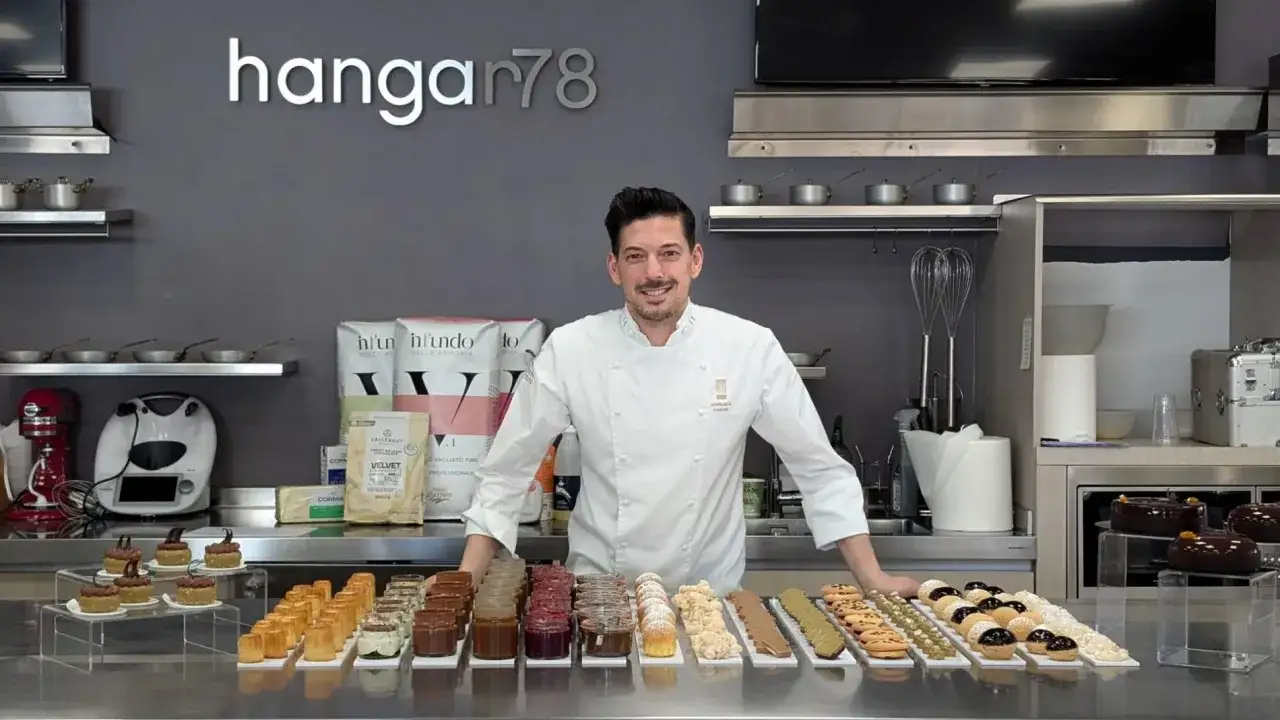 Pasticcere sorridente in cucina con dolci e ingredienti. Chiss&agrave; quanto guadagna un pasticcere con tanta passione!