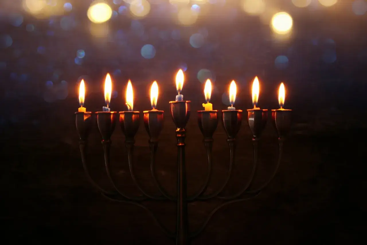 Płonące świece na chanukii, symbolizujące cud chanuki, w blasku świateł.