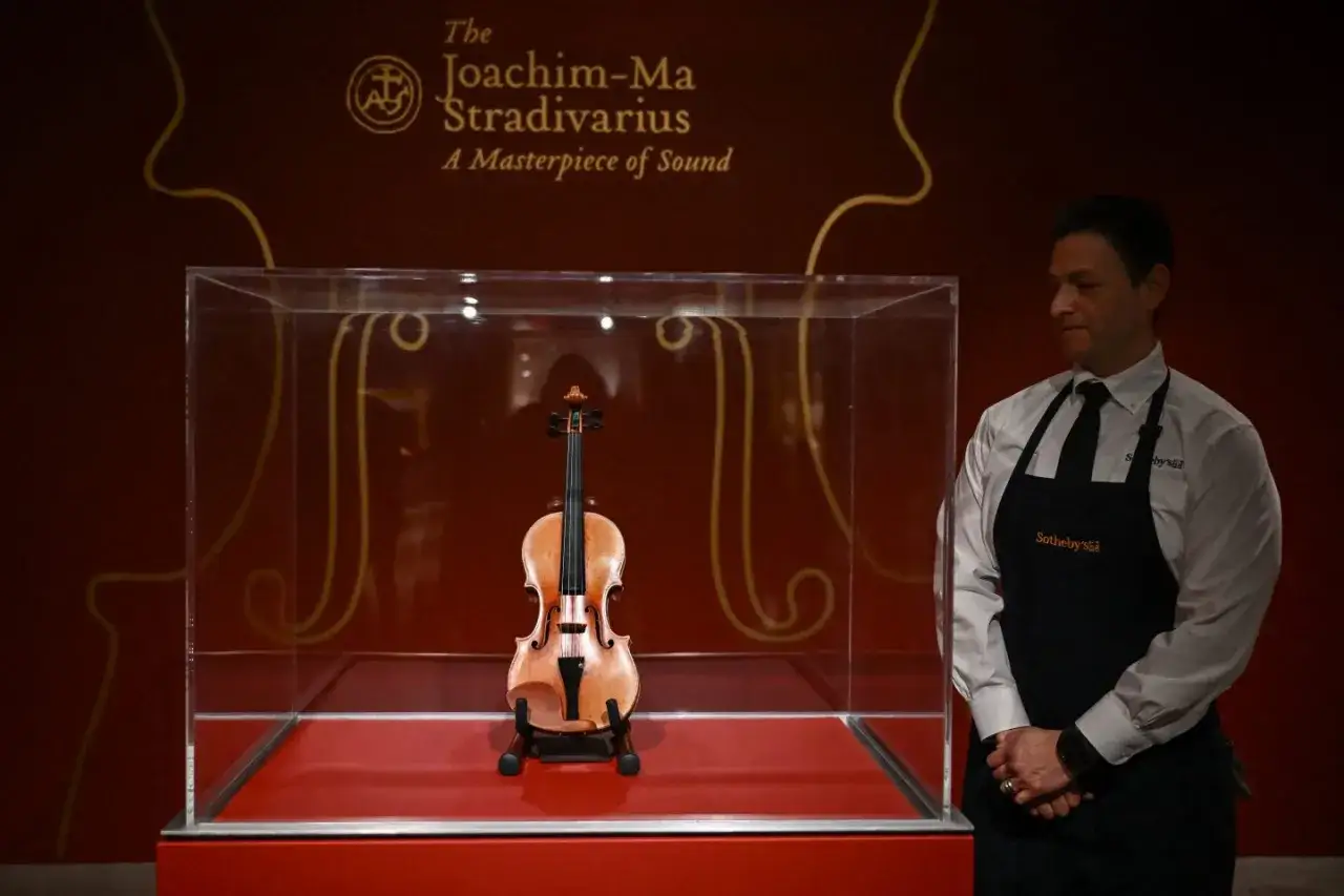 Joachim-Ma Stradivarius, najdroższy instrument świata, w gablocie. Obok stoi pracownik Sotheby's.