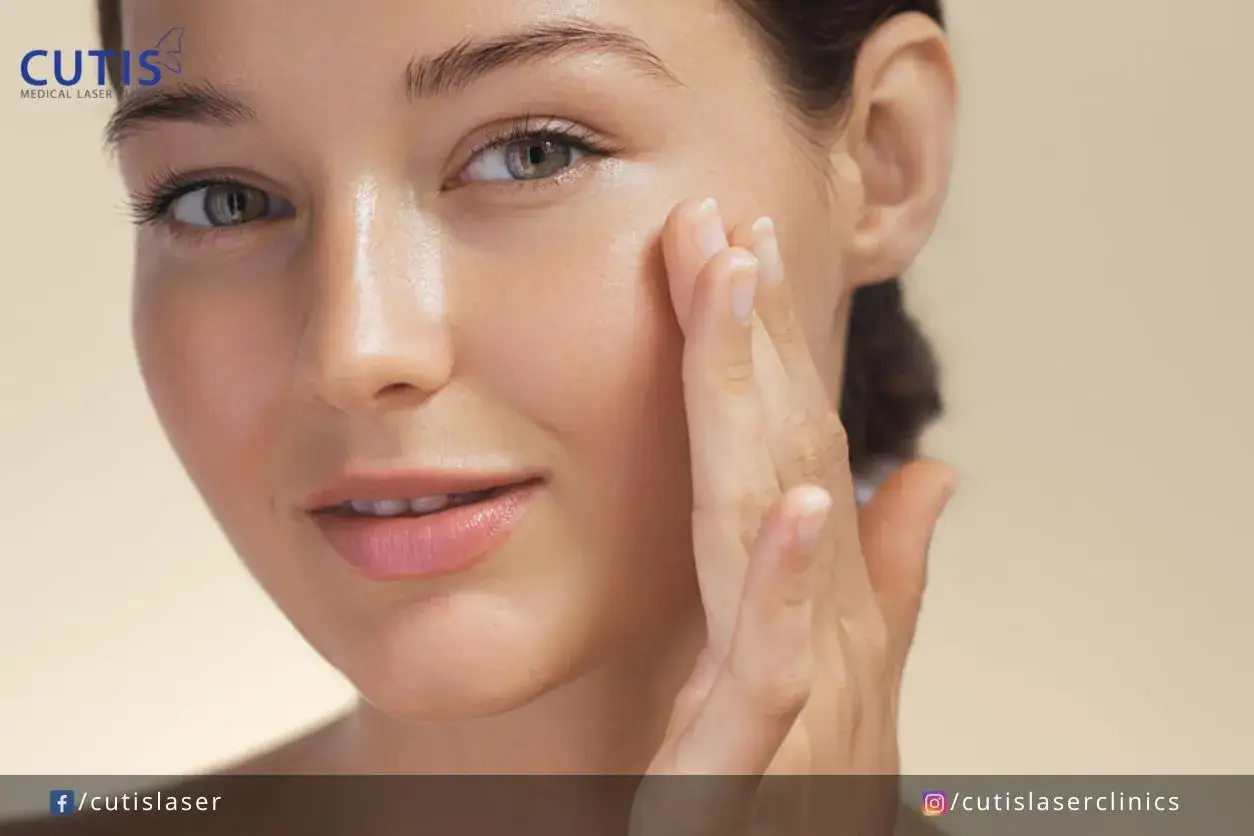 Mujer con piel glowy, tocando su rostro con delicadeza. Su piel luce radiante y saludable.