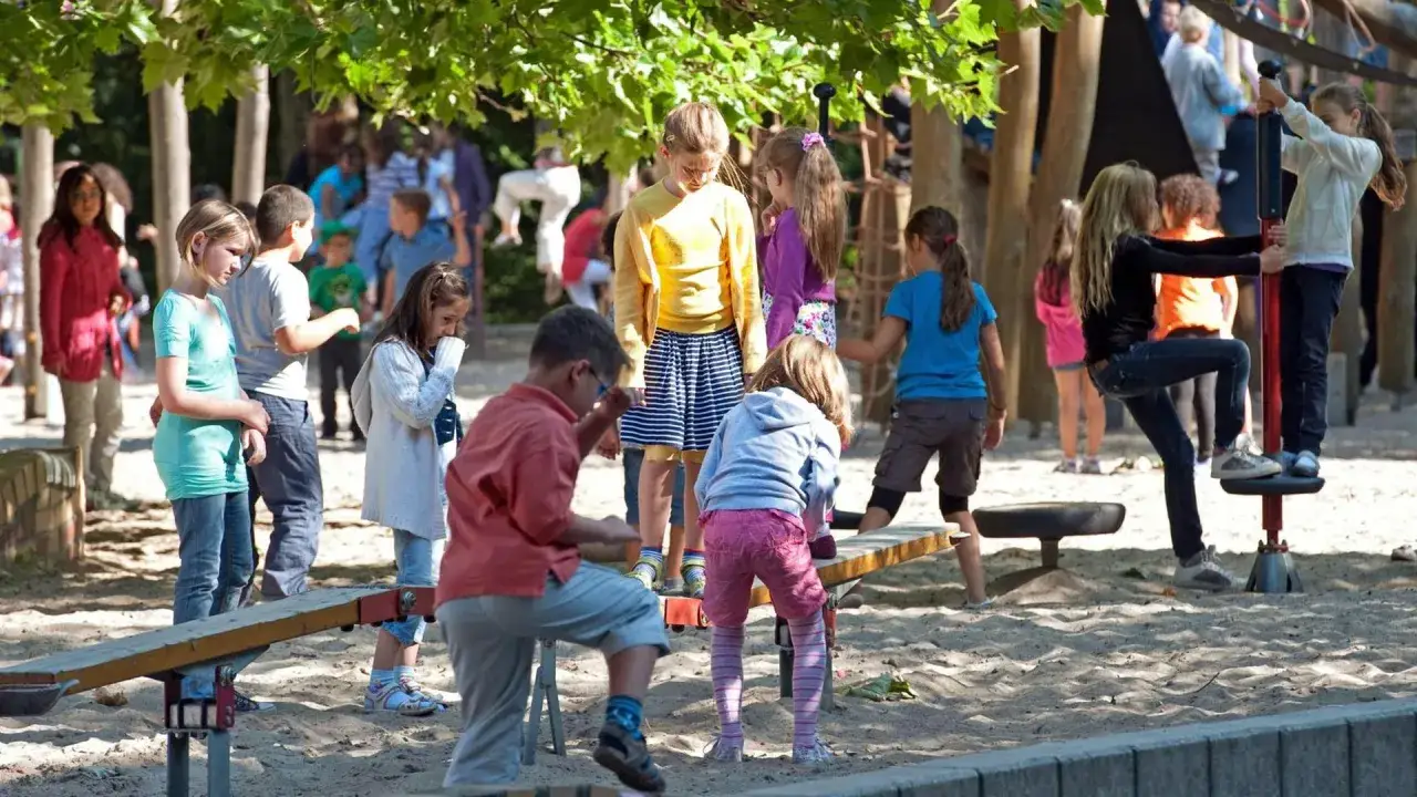 Kinder spielen und lachen auf einem Spielplatz. Sie sind Freunde, die gemeinsam Spaß haben und die Sonne genießen.