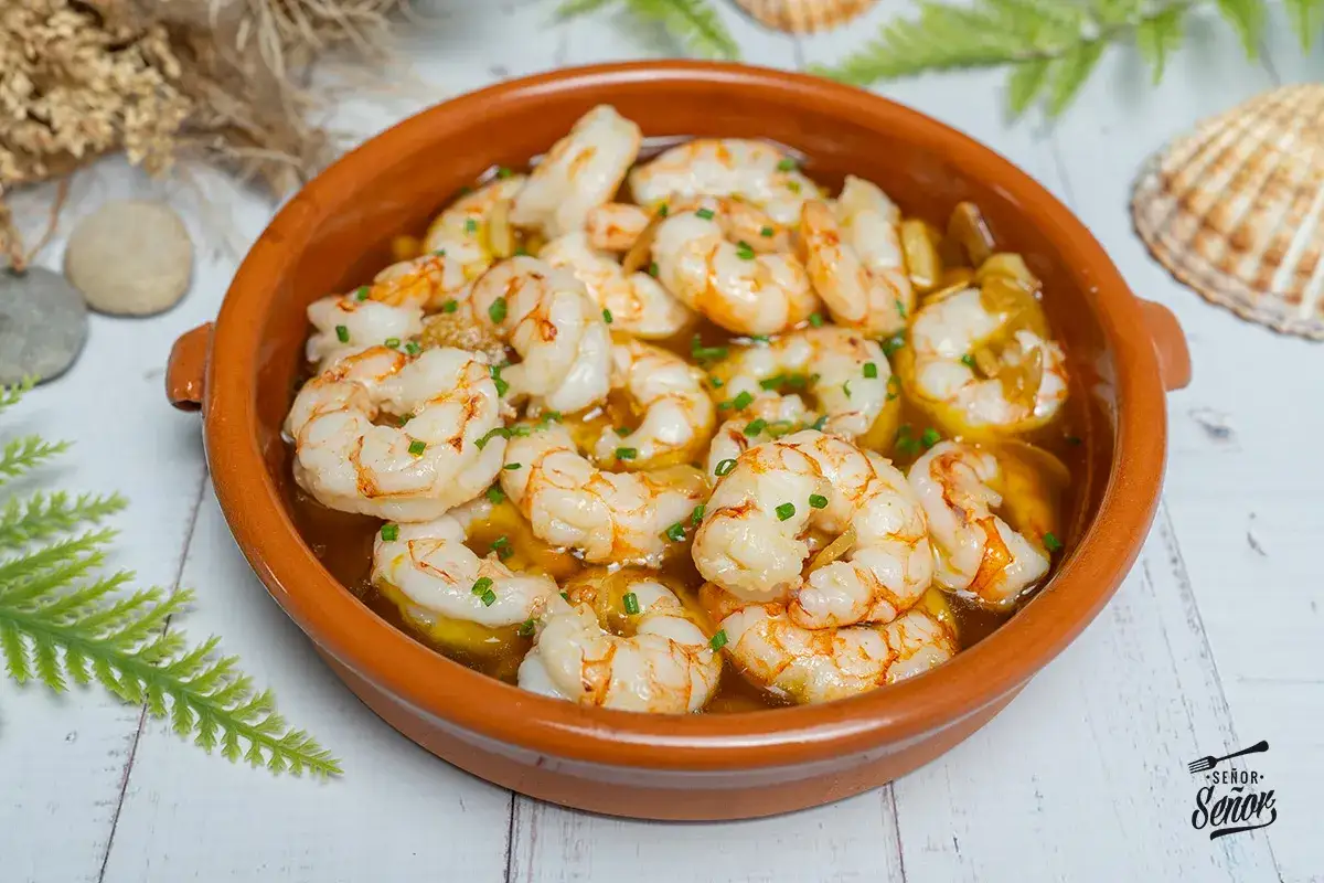 Gambas al ajillo, una receta española irresistible. Camarones jugosos en aceite de oliva con ajo y perejil, servidos en cazuela de barro.