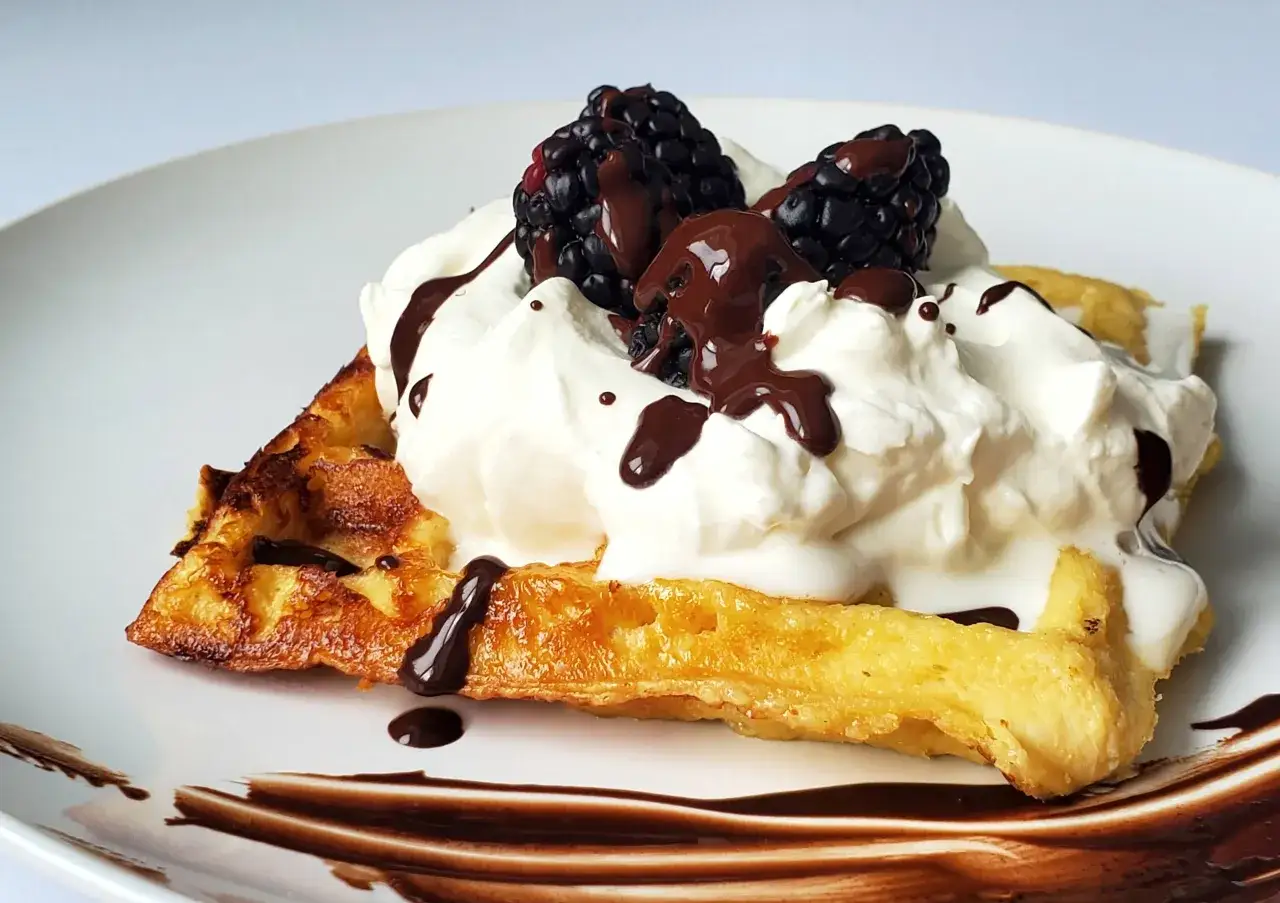 Pyszne keto gofry z mascarpone, jeżynami i polewą czekoladową na białym talerzu.