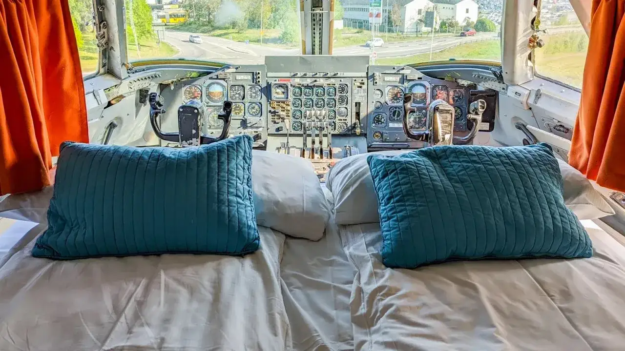 En säng med blå kuddar framför cockpit i en jumbo stay.