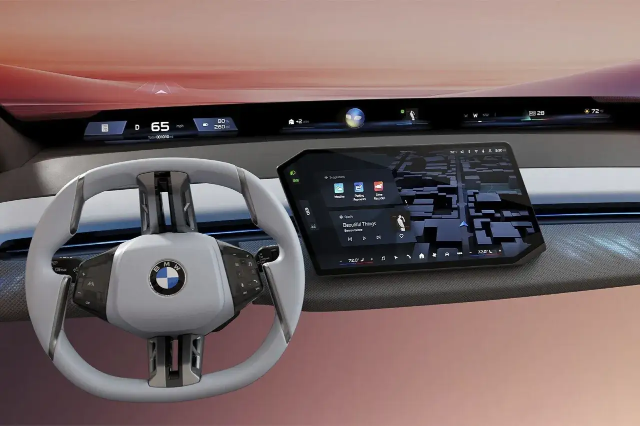 Nowoczesne wnętrze BMW z ekranem pokazującym mapę, muzykę i funkcje, jak w CarPlay. Kierownica i cyfrowe wskaźniki dopełniają obrazu.