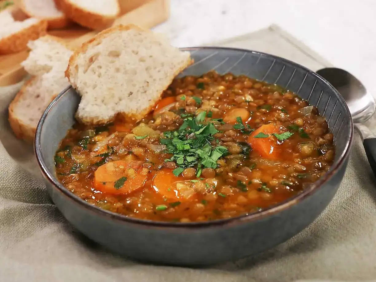 Varm linssoppa med morötter och persilja, perfekt för ett enkelt linssoppa recept. Serveras med bröd.