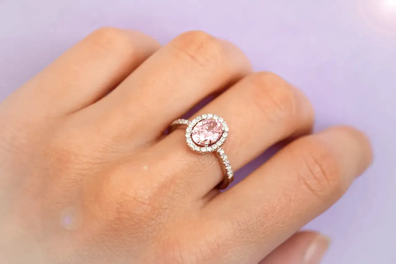 Anello con pietra rosa, simbolo di amore e purezza. La sua luce delicata illumina la mano, un promemoria del suo profondo significato.