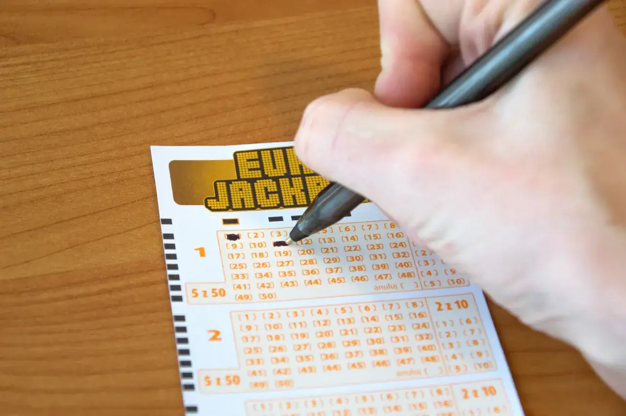 Ręka zaznacza liczby na kuponie Eurojackpot. Dlaczego influencerzy twierdzą, że to strata pieniędzy?