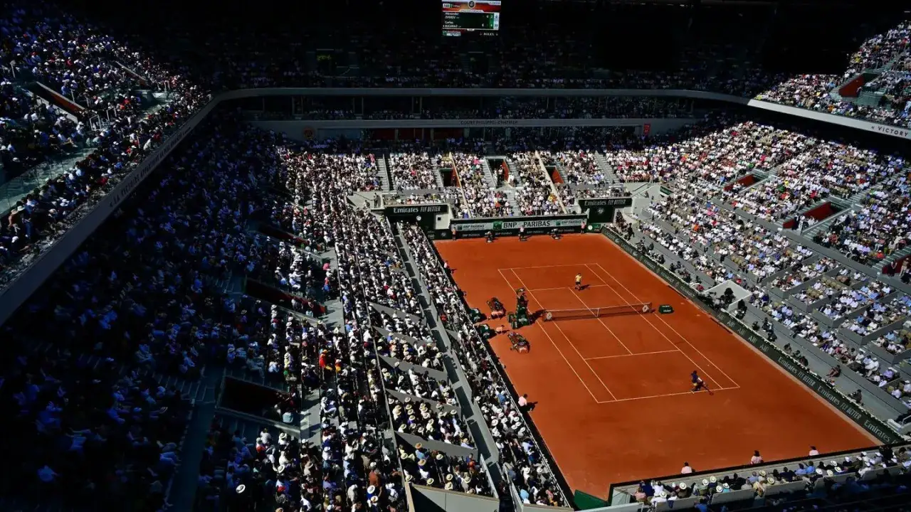Roland Garros finał mężczyzn. Dwa korty ziemne, pełne trybun kibic&oacute;w, w słoneczny dzień.