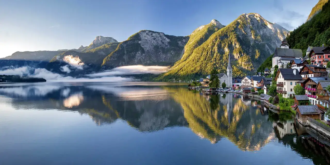 Malerisches Dorf am Salzburg See, Berge spiegeln sich im ruhigen Wasser.