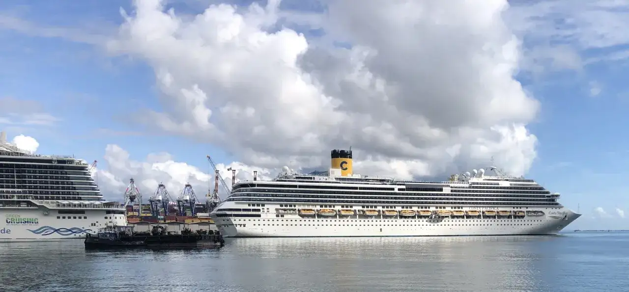 Grandi navi da crociera attraccate al terminal crociere La Spezia, con gru portuali sullo sfondo e un cielo nuvoloso.