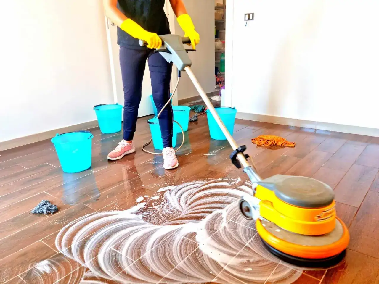 Pulizia profonda del finto parquet gres con lucidatrice. La persona con guanti gialli usa la macchina per un risultato brillante.