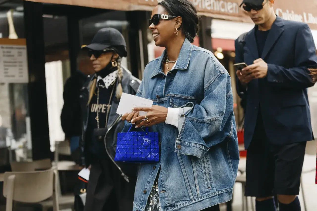 Mujeres con estilo urbano, una con chaqueta vaquera oversize y bolso azul, ideal para disimular caderas y muslos.