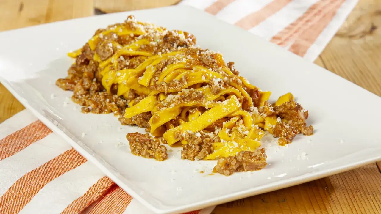 Tagliatelle fresche condite con un ricco ragù di carne e una spolverata di parmigiano.