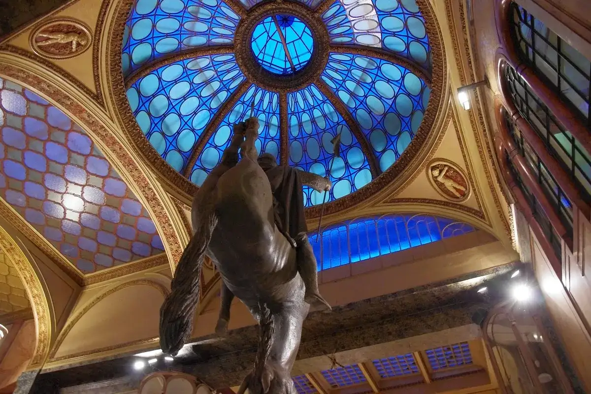Statue équestre inversée sous le dôme bleu du passage Lucerna à Prague.