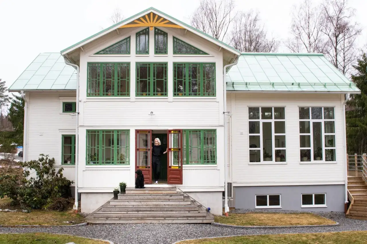 Vacker vit villa med gröna fönster och en inbjudande glasveranda. Inspiration för ditt drömhem.
