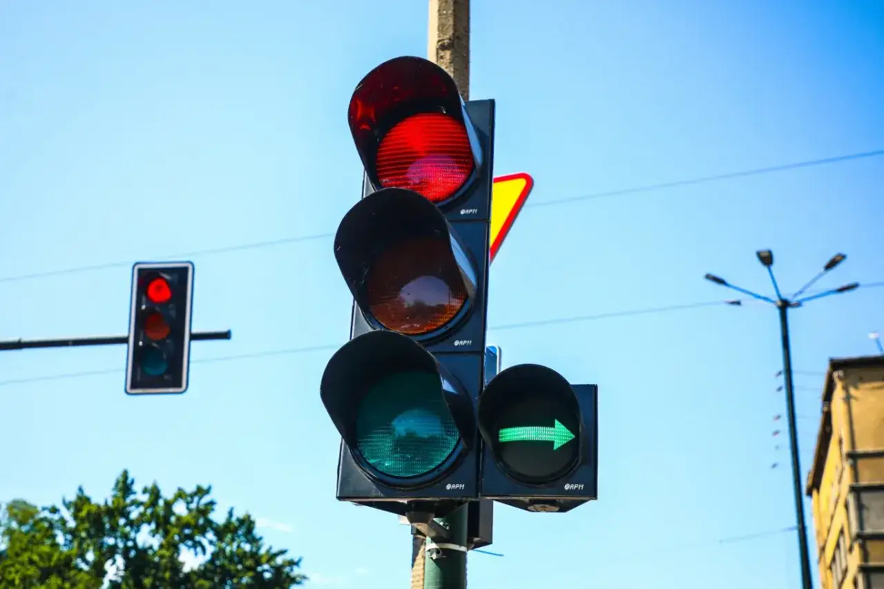 Sygnalizacja świetlna z czerwonym światłem, które może oznaczać mandat za stop. Zielona strzałka pozwala jechać.