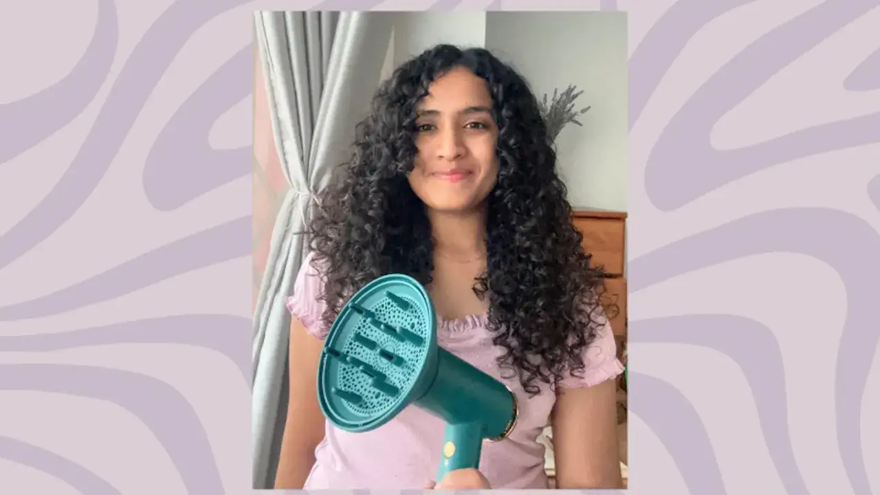 Frau mit vollen Locken hält Diffusor-Aufsatz für den Föhn. Perfekt für die Curly Girl Methode!