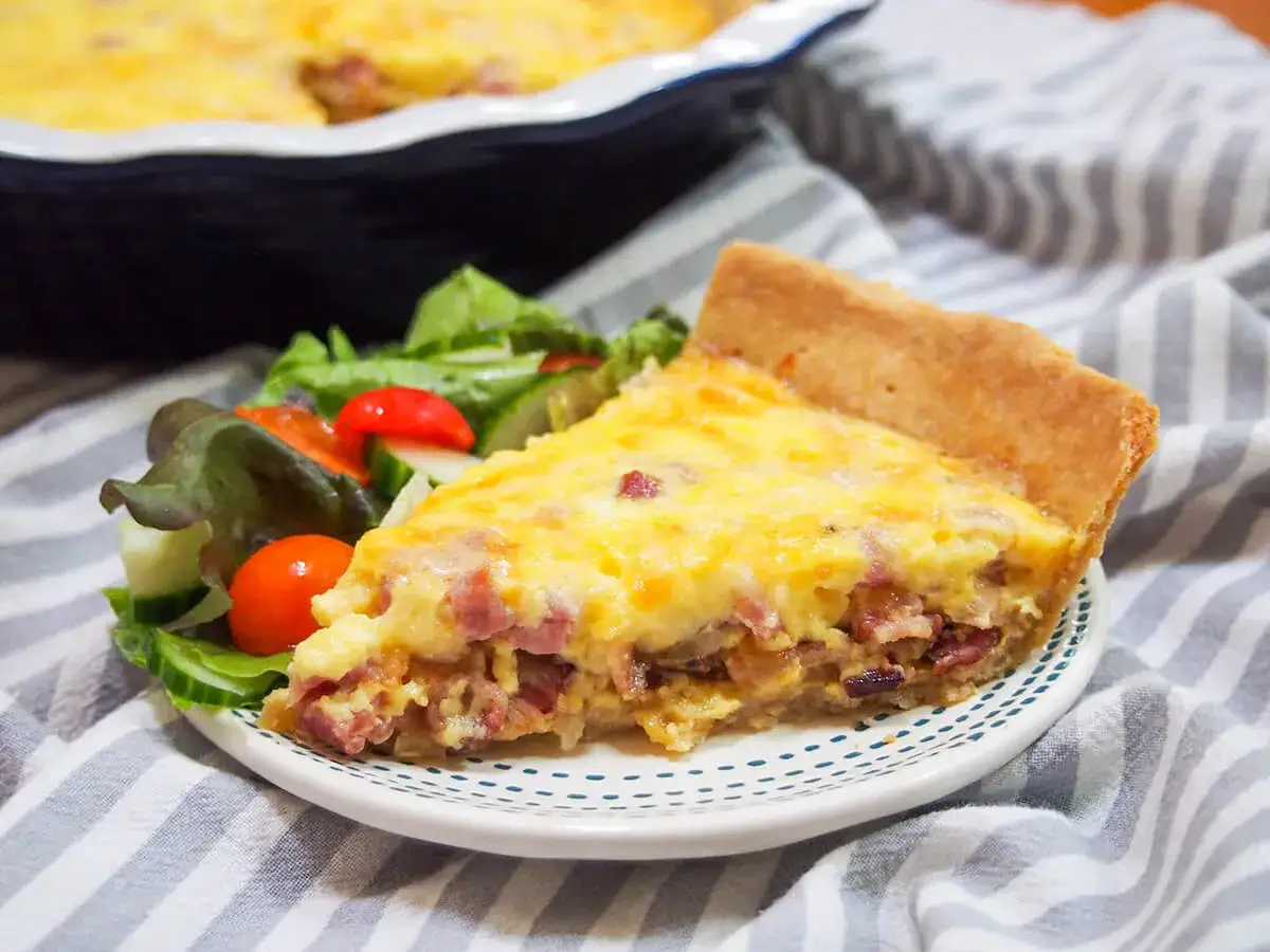 En bit kr&auml;mig quiche lorraine med bacon och ost, serverad med en fr&auml;sch sallad.