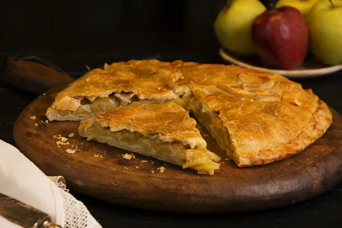 Empanada de manzana de la abuela, dorada y casera, con una porción lista para disfrutar.