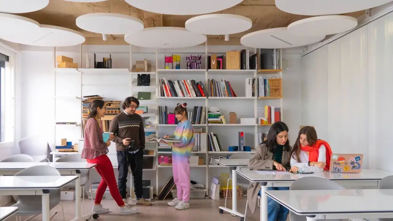 Estudiantes colaboran en un aula moderna, inspiradora para quienes buscan donde estudiar dise&ntilde;o gr&aacute;fico.