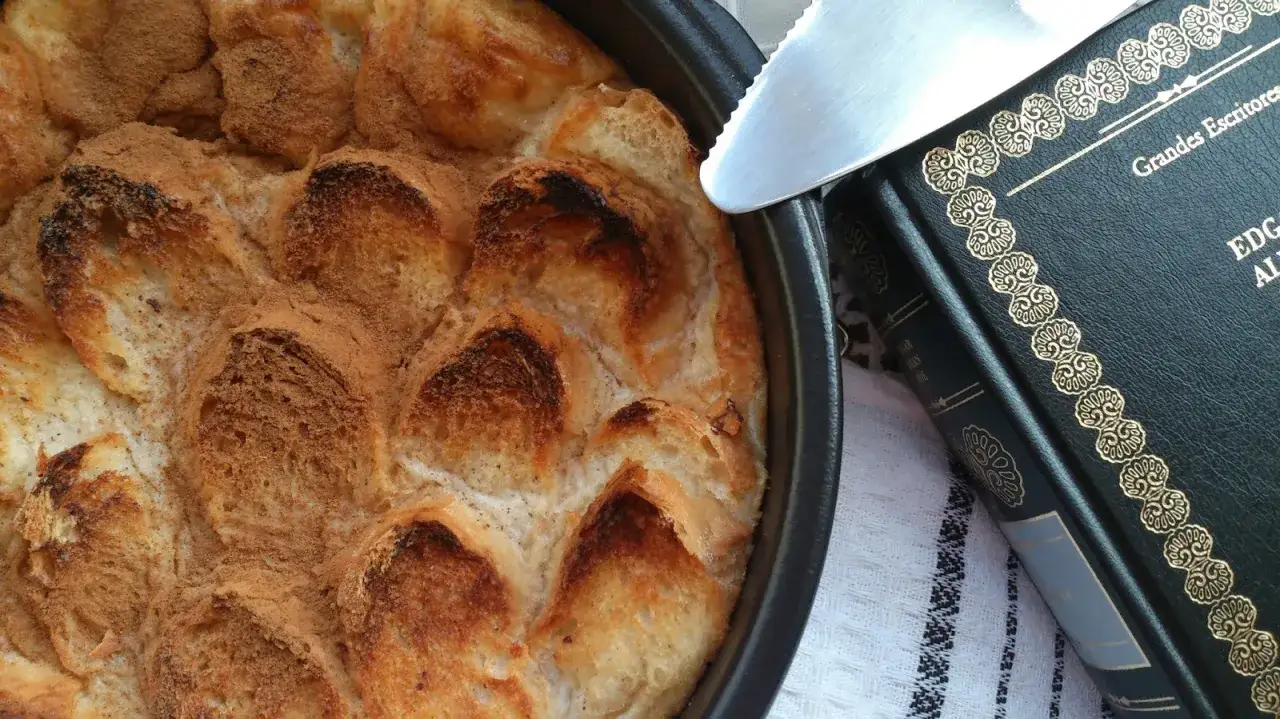 Delicioso pudin de pan recién horneado, espolvoreado con canela, junto a un libro de 