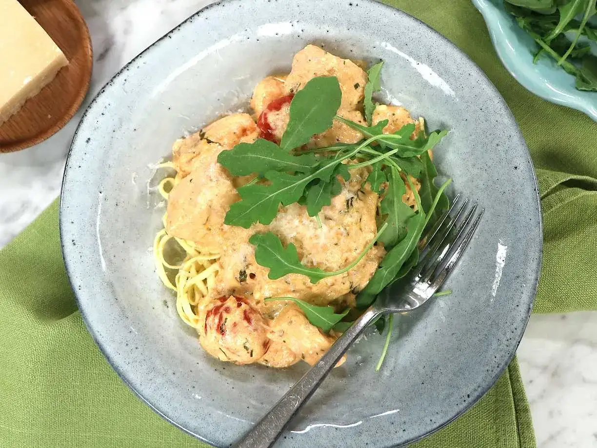 En kr&auml;mig laxpasta i ugn med k&ouml;rsb&auml;rstomater och ruccola. Serveras i en vacker sk&aring;l med en gaffel.