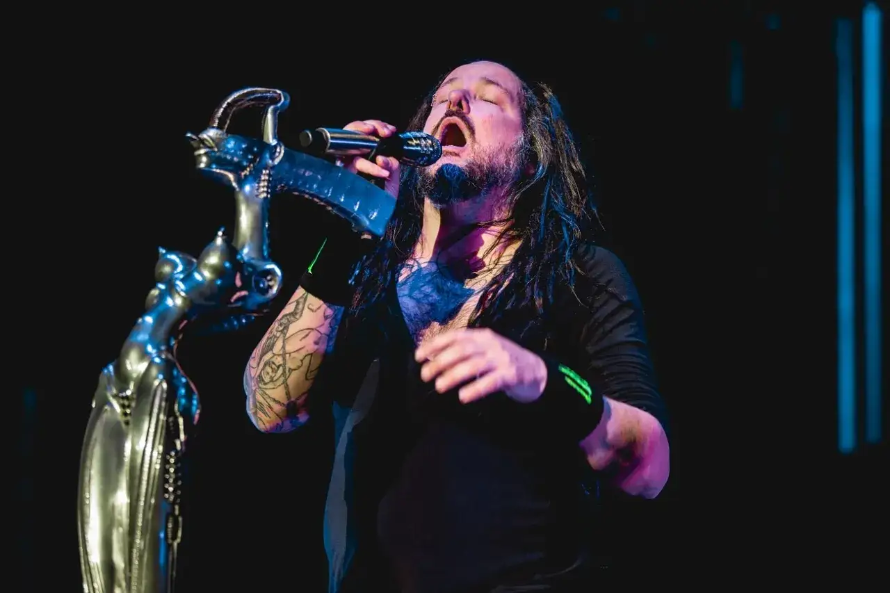Le chanteur de Korn, Jonathan Davis, chante avec passion dans un micro, son visage illumin&eacute; par les projecteurs.