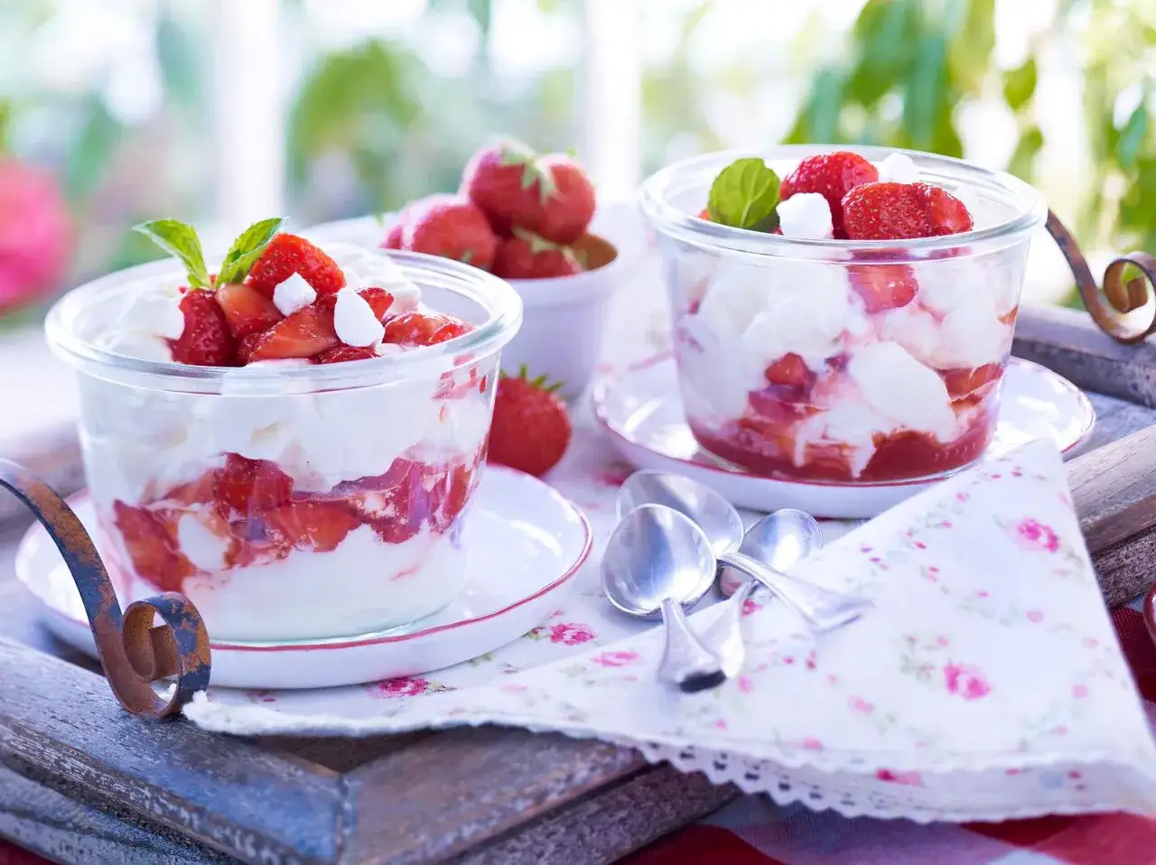 Zwei Gl&auml;ser mit Eton Mess, geschichtet aus Sahne, zerbrochenem Baiser und frischen Erdbeeren, garniert mit Minze.