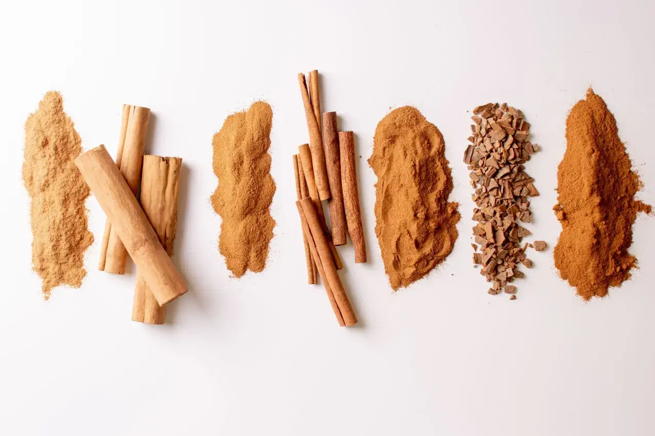 Piles de cannelle en poudre, bâtons et éclats sur fond blanc. Un délice pour les sens.