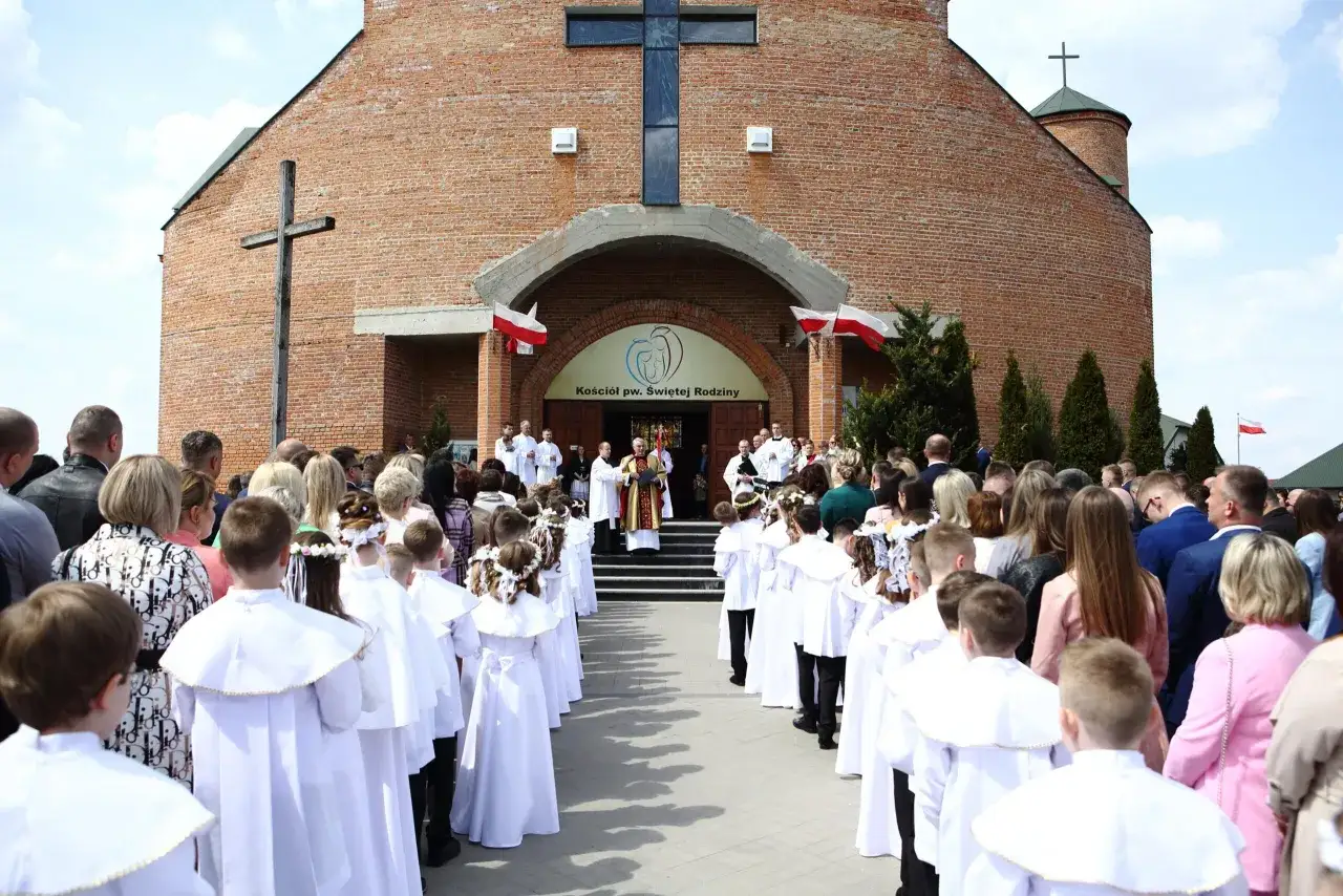 Dzieci w białych strojach czekają przed kościołem, kiedy jest komunia.