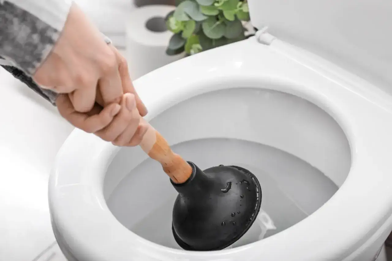 Hand mit Saugglocke versucht, eine verstopfte Toilette zu befreien.