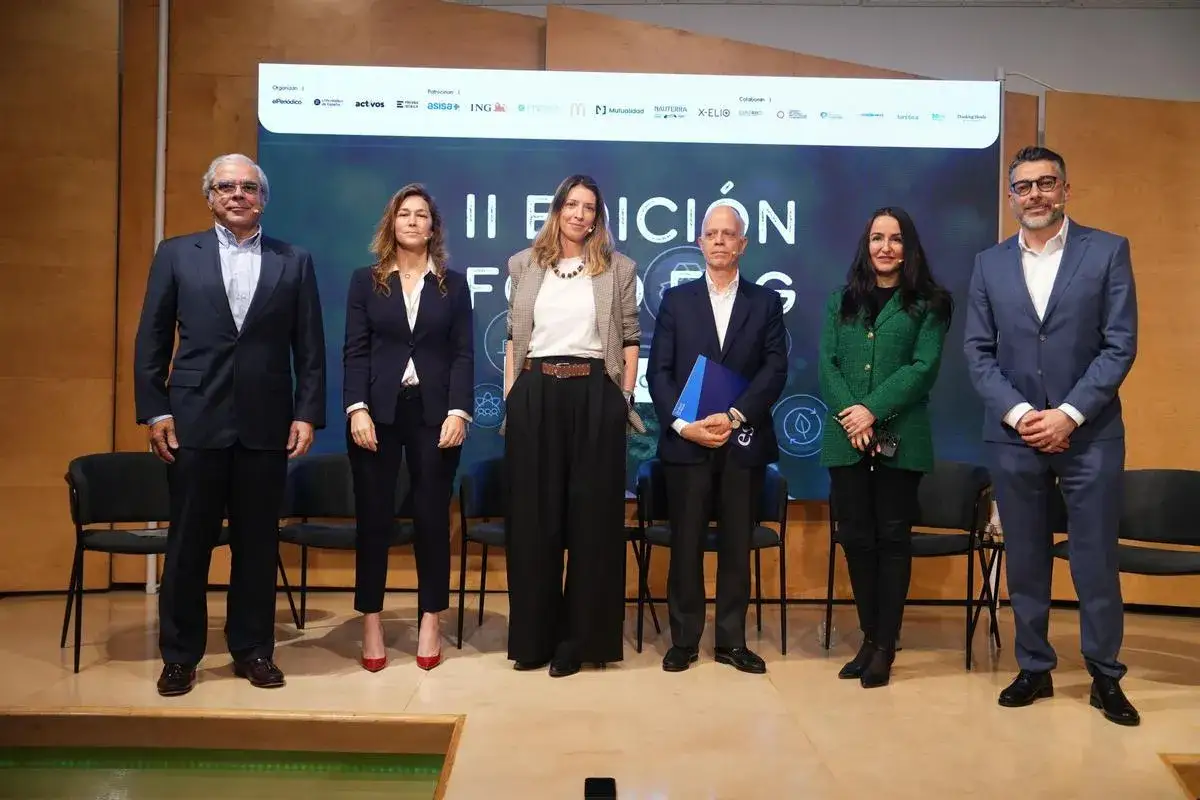 Cinco personas posan en un escenario, con un cartel de 