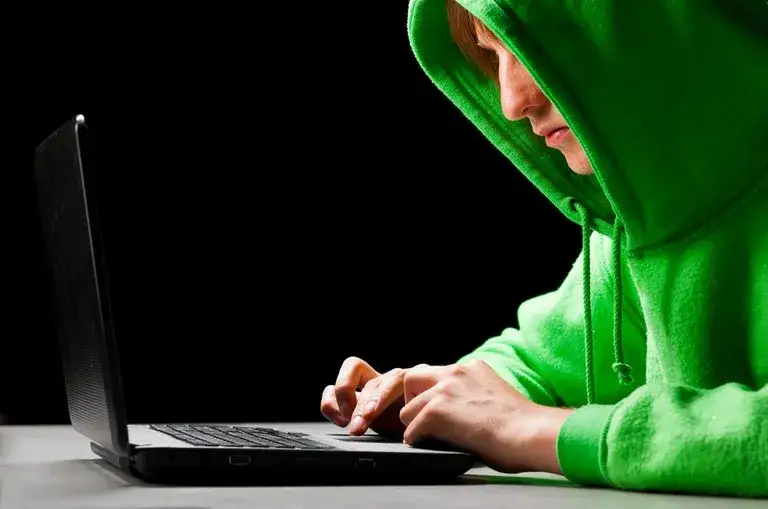 Młoda osoba używająca smartfona, z rozmazanym tłem symbolizującym sieć i niebezpieczeństwo