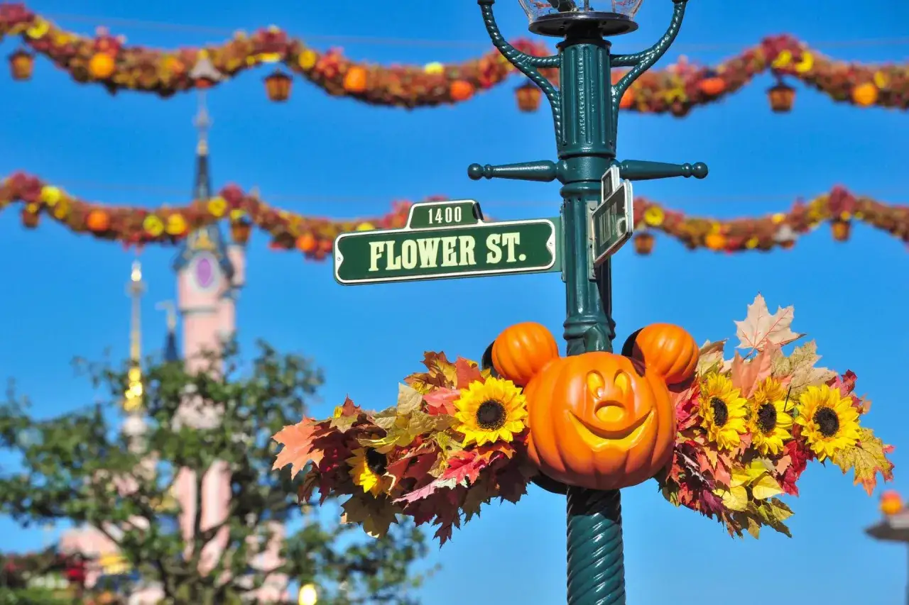 Decoración de **Disneyland Paris Halloween** con calabazas, girasoles y hojas de otoño adornan un poste de luz con el letrero 