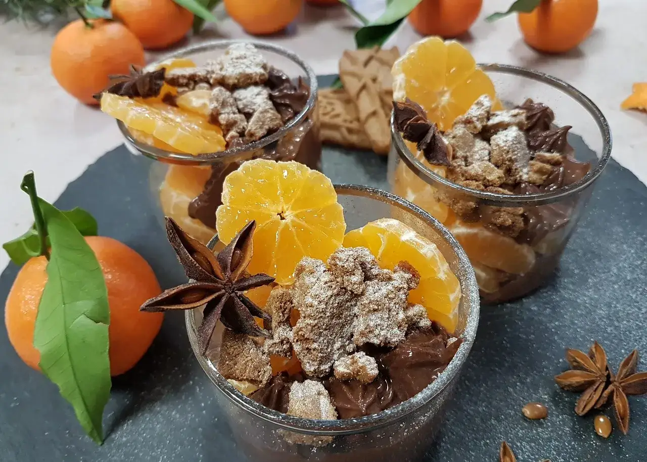 Trois verrines de recette mousse au chocolat onctueuse, garnies de clémentines, biscuits émiettés et anis étoilé.