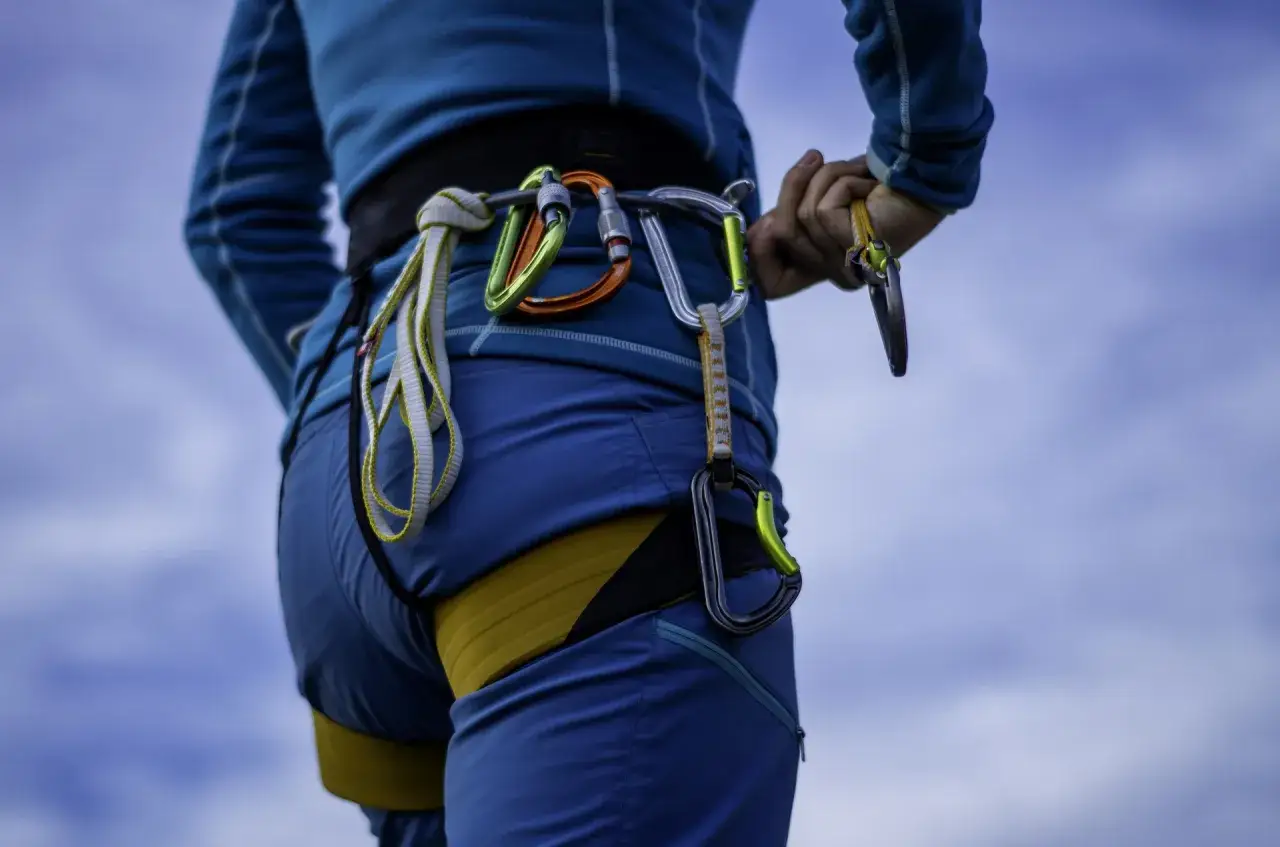Wspinaczka wysokogórska: alpinista w niebieskim stroju z uprzężą i karabinkami, gotowy na wyzwanie.